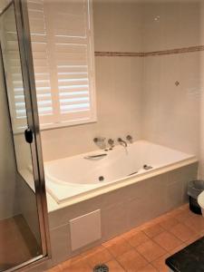 a bathroom with a bath tub with a window at Sunrise Luxury Apartments in Tuncurry