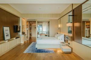 上海市にあるThe Anandi Hotel and SPA - Luxury Healing Hotel for Wellbeingの広いベッドルーム(ベッド1台付)、リビングルームが備わります。
