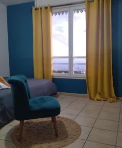 Habitación azul con silla y ventana en Le Bel Horizon, en Le Tampon