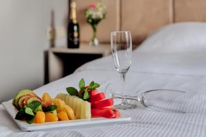 un piatto di frutta e un bicchiere di vino su un letto di Citi Hotel's Warszawa-Falenty a Raszyn