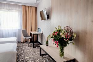 una habitación de hotel con un jarrón de flores sobre una mesa en Citi Hotel's Warszawa-Falenty, en Raszyn