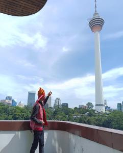 una mujer de pie en una cornisa mirando la torre del Seattle en The Maple Suite, en Kuala Lumpur