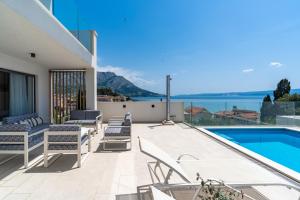 a patio with chairs and a swimming pool at Luxurious VILLA LAPIS - heated pool, sauna, gym and spa, 120m to sandy beach in Omiš
