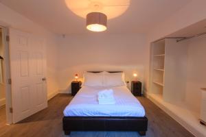 a bedroom with a bed with white sheets and a light at Wellington View: Ground floor apartment with sea views and garden in Kent