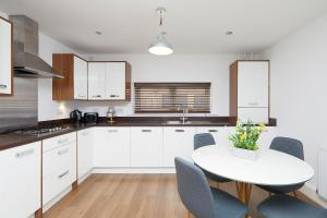 a kitchen with white cabinets and a white table and chairs at Derby Train Station Roof Terrace House in Derby
