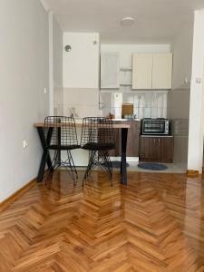 a kitchen with a wooden floor and chairs and a table at Comfy Studio - 1 minute walk to Delta Planet in Niš