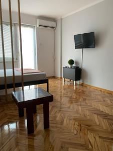 a room with a bed and a tv and a wooden floor at Comfy Studio - 1 minute walk to Delta Planet in Niš