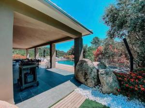an outdoor patio with a table and a rock at CASA GIABICONI Villa 10 personnes piscine & spa in Sainte-Lucie de Porto-Vecchio