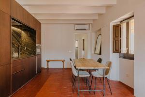 eine Küche und ein Esszimmer mit einem Holztisch und Stühlen in der Unterkunft Flateli Santa Clara 21 in Girona