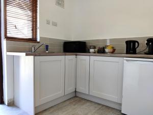 uma cozinha com armários brancos e uma bancada em Foxhollow House Suite em Blarney