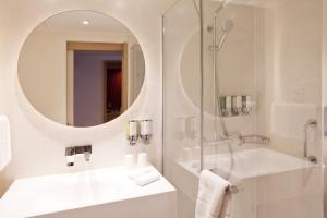 雷根斯堡Hampton By Hilton Regensburg的带淋浴、水槽和镜子的浴室