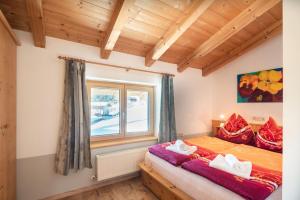um quarto com uma cama com almofadas vermelhas e uma janela em Ski in - Ski out Panoramaferienhaus Breitmoos neben Mittelstation em Mittersill