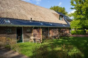 ein Haus mit Stühlen und einem Strohdach in der Unterkunft Herberg De Fazant in Oudemolen