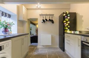 a kitchen with white cabinets and a sink at Romantic cottage, Old Town, Hebden Bridge in Heptonstall