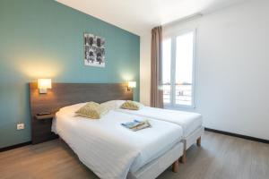 - une chambre avec un grand lit et une grande fenêtre dans l'établissement Zenitude Hôtel-Résidences Nîmes Centre, à Nîmes