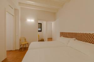a white bedroom with two beds and a chair at Flateli Santa Clara 12 in Girona