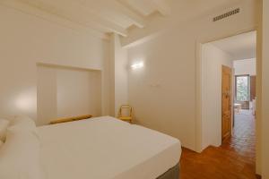 a white bedroom with a bed and a hallway at Flateli Santa Clara 12 in Girona