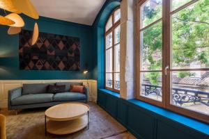 uma sala de estar com um sofá, uma mesa e janelas em HONORÊ SUITE SAINT NIZIER em Lyon