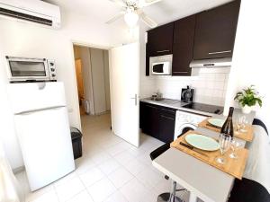 a kitchen with a table and a white refrigerator at 2P 42m² Terrasse / Piscine / Clim / Plage ! in Juan-les-Pins