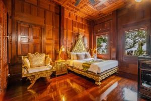 a bedroom with a king sized bed and a chair at Royal Thai Villa Phuket - SHA Extra Plus in Rawai Beach