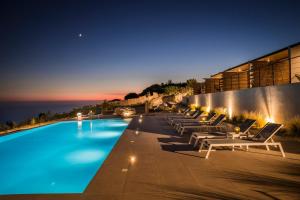 einen Pool mit Liegestühlen und das Meer in der Nacht in der Unterkunft Kefalonian Escape Suites in Valeriános