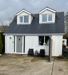 ein weißes Haus mit einem schwarzen Dach und zwei Stühlen in der Unterkunft The Bolt Hole Hythe panoramic coast and sea views in Kent