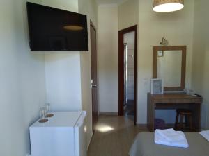 a room with a refrigerator and a desk with a television at Ilios Hotel in Lákka