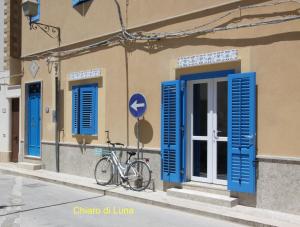 a bike parked in front of a building with blue shutters at La Luna e il Gatto in Favignana