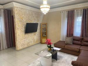 a living room with a couch and a tv on a wall at RÉSIDENCE MARTHA in Yaoundé