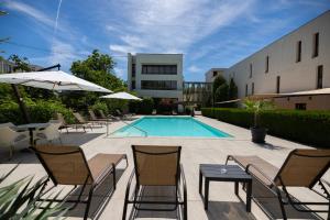 a swimming pool with chairs and a table and a building at Hotel Perla in Timişoara