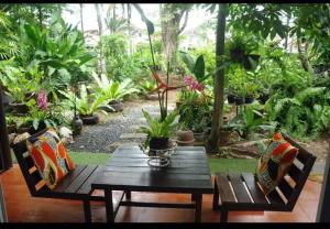 uma mesa de madeira e cadeiras num jardim com plantas em Eat n Sleep em Phuket