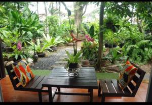 a wooden table and chairs in a garden with plants at Eat n Sleep in Phuket Town