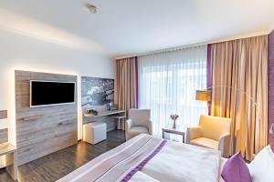 a hotel room with a bed and a tv at Parkhotel Sonnenberg in Eltville