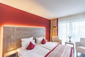 Cette chambre comprend un grand lit aux murs rouges. dans l'établissement Parkhotel Sonnenberg, à Eltville