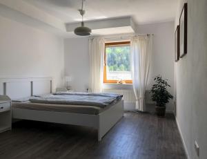 a white bedroom with a bed and a window at Ferienwohnung Am Sonnenhang in Enzklösterle