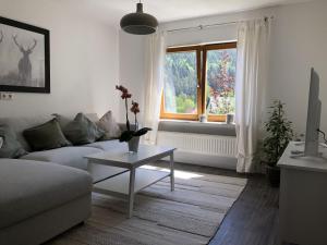 sala de estar con sofá, mesa y ventana en Ferienwohnung Am Sonnenhang, en Enzklösterle