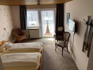 a hotel room with two beds and a chair at Pension Florianhof in Schonach