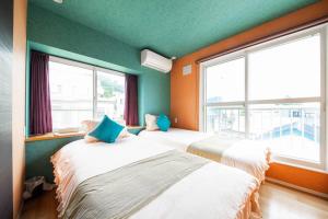 two beds in a room with green walls and windows at THE BEEHIVE AIOI in Otaru