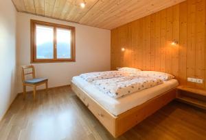 um quarto com uma cama e uma cadeira em Haus Helga em Schoppernau