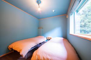 Duas camas num quarto azul com uma janela em THE FAM em Nakafurano