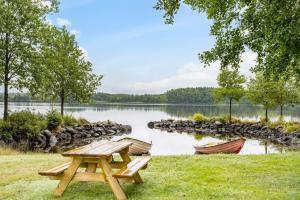 ein Picknicktisch und zwei Boote auf einem See in der Unterkunft Lovely holiday home in the village of Flattinge, with a view of lake Flaren in Vittaryd