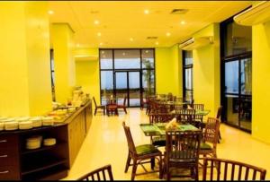 comedor con mesas y sillas y paredes amarillas en Tropical Executive Vista Maravilhosa, en Manaus
