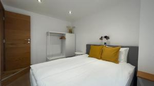 una camera con un letto bianco con due cuscini gialli di SeaHouse Apartments a Piran