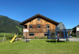 ein Holzgebäude mit einem Spielplatz davor in der Unterkunft Haus Helga in Schoppernau