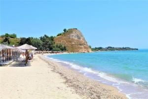 a beach with chairs and umbrellas and the ocean at Αξέχαστη διαμονή - Unforgettable accommodation in Nea Kalikratia