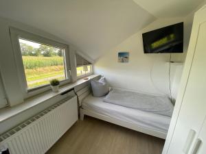 a small room with a bed and a window at Etzel-Lodge Feldblick in Friedeburg
