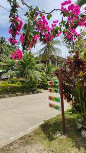 un panneau devant une route aux fleurs roses dans l'établissement Reggae Vibes De Romblon, à Agpanabat