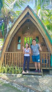 2 personnes debout devant une petite maison dans l'établissement Reggae Vibes De Romblon, à Agpanabat