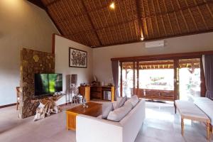 a living room with a couch and a tv at Puri Andong Villa in Ubud
