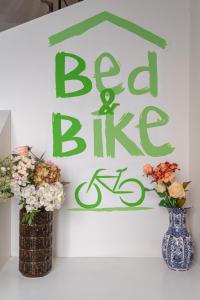 uma placa que diz bicicleta cama e dois vasos com flores em Bed & Bike Ferrara em Ferrara